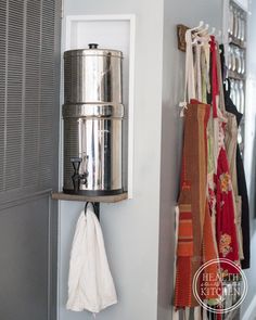 there is a metal pot hanging on the wall next to a towel rack with towels