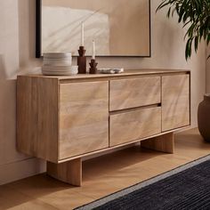 a wooden dresser sitting next to a potted plant in front of a mirror on the wall