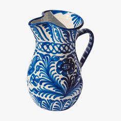 a blue and white pitcher with an intricate design on the bottom, sitting in front of a white background