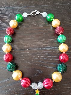 "Christmas Inspired Christmas Tree Children's Chunky Bubblegum Bead Necklace & Bracelet Set/ Holidays This very cute Christmas Tree Necklace & Bracelet Set is a perfect addition to any holiday outfit and the holiday season. The Necklace is made up primarily of 20mm beads in shades of red, green and yellow gold. The necklace measures approximately 11\" when toggled around neck including the Christmas Tree pendant. The Bracelet is an elastic bracelet, doubled up for extra strength. The Nec Christmas Party Beaded Necklaces With Round Beads, Christmas Party Round Bead Necklaces, Festive Christmas Beads With Round Shape, Holiday Festive Jewelry With Colorful Beads, Festive Holiday Jewelry With Colorful Beads, Festive Christmas Beads, Christmas Festive Round Beads, Christmas Beaded Necklaces With Colorful Beads For Gift, Christmas Gift Colorful Beaded Necklaces