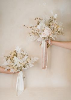 two brides holding bouquets of flowers in their hands on a beige background with white ribbons