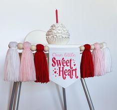 a cupcake on top of a cake stand with tassels hanging from it