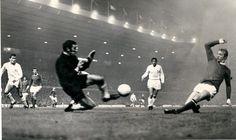 an old black and white photo of soccer players kicking the ball in front of spectators