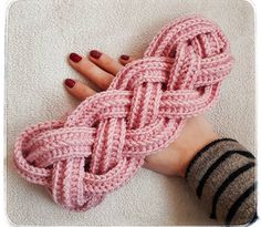 a woman's hand with red nail polish holding a pink crochet bracelet