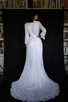 the back of a woman's white wedding dress in front of a bookcase