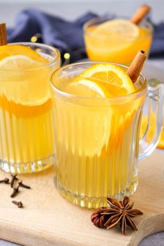 two mugs filled with orange juice and cinnamon