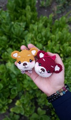 two crocheted teddy bears sitting on top of each other in front of green plants