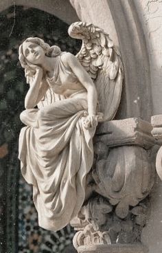 an angel statue sitting on the side of a building