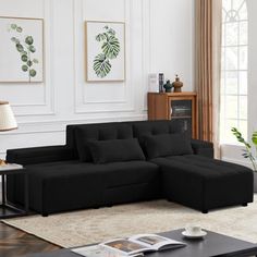 a living room with black couches and coffee table in front of the wall paintings