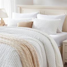 a white bed topped with pillows and blankets