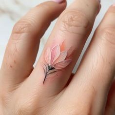 a woman's hand with a pink flower tattoo on her left thumb and finger