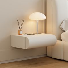 a white table with a lamp on it next to a bed