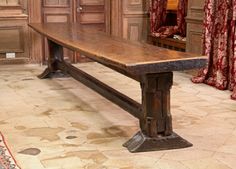 an old wooden table in a room with red curtains