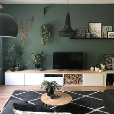 a living room filled with furniture and plants on top of a wooden table in front of a flat screen tv