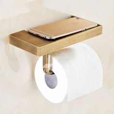 a cell phone is sitting on top of a toilet paper holder that has a roll of toilet paper in it