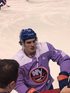 a hockey player standing next to another player on an ice rink with other players in the background