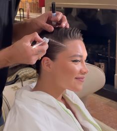 a woman getting her hair cut by a man