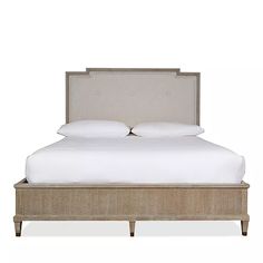 an upholstered bed with white sheets and pillows