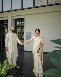 a man and woman standing next to each other in front of a building holding hands