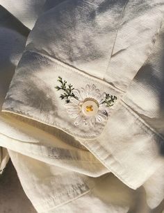 a white shirt with embroidered flowers on the front and back, sitting on top of a bed