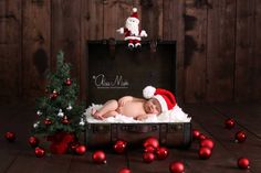 a newborn baby is laying in an old suitcase with christmas decorations on the floor next to it