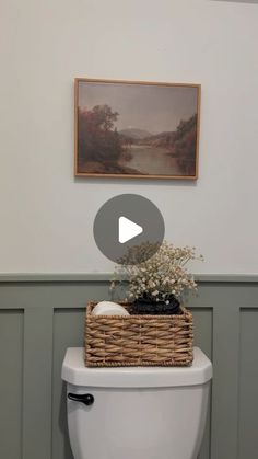 a white toilet sitting in a bathroom next to a basket with flowers on top of it