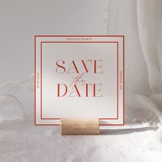 a save the date card with a rubber stamp on it sitting on top of a bed