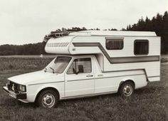 an old white truck with a camper attached to it's back parked in a field