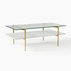 a glass and brass coffee table with two shelves on each side, against a white background