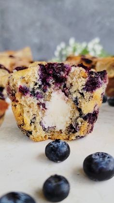 blueberry muffins cut in half on a table with fresh blueberries around them