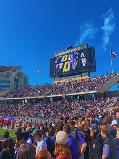 a large stadium filled with people watching a football game on a big screen tv in the middle of the field