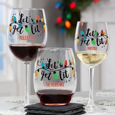 three wine glasses sitting on top of a table next to each other with christmas lights in the background