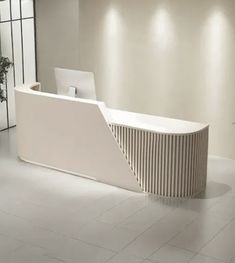 a white reception table with a laptop on it's desk in an office setting