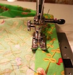 the sewing machine is on top of the green table cloth with scissors and thread in it