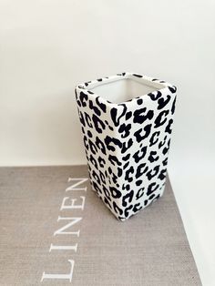 a black and white animal print vase sitting on top of a table next to a sign