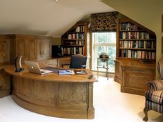 a desk with a laptop on top of it in front of a bookcase and chair