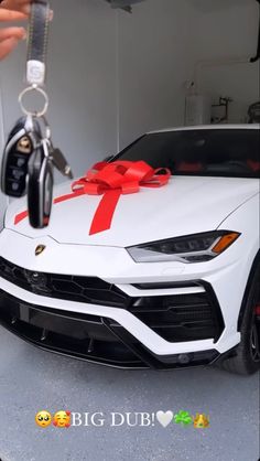 a white sports car with a red bow tied around it's hood and keychain