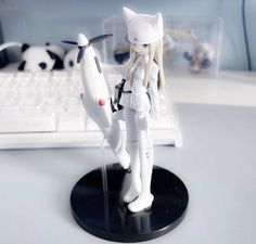 a white cat figurine standing next to a keyboard