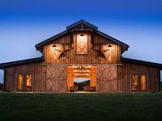 a barn with two clocks on the side of it's front door at night