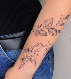 a woman's arm with flowers and leaves tattooed on the left side of her arm