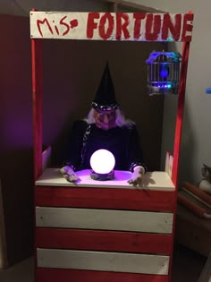 a man dressed in costume sitting at a desk with a light up ball on it