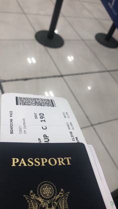 a black passport sitting on top of a white tiled floor next to a metal pole