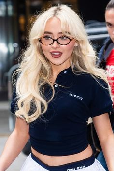 a blonde woman with glasses walking down the street