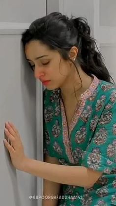 a woman leaning against a refrigerator with her hand on the door