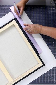 a person is making a frame out of paper and glues it on the table