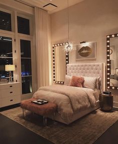 a bedroom with a bed, mirror and lights on the wall above it's headboard