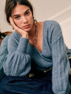 a woman sitting on the floor with her hand under her chin and looking at the camera