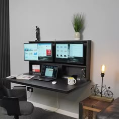 a desk with two monitors and a laptop on it in front of a wall mounted monitor