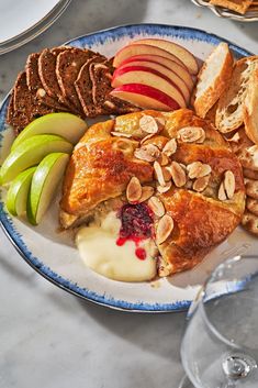 a white plate topped with fruit and crackers next to wine glasses on a table