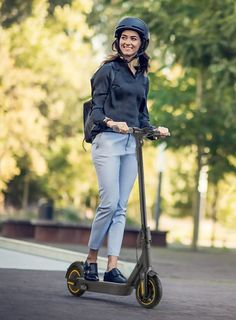 a woman is riding an electric scooter on the street with trees in the background